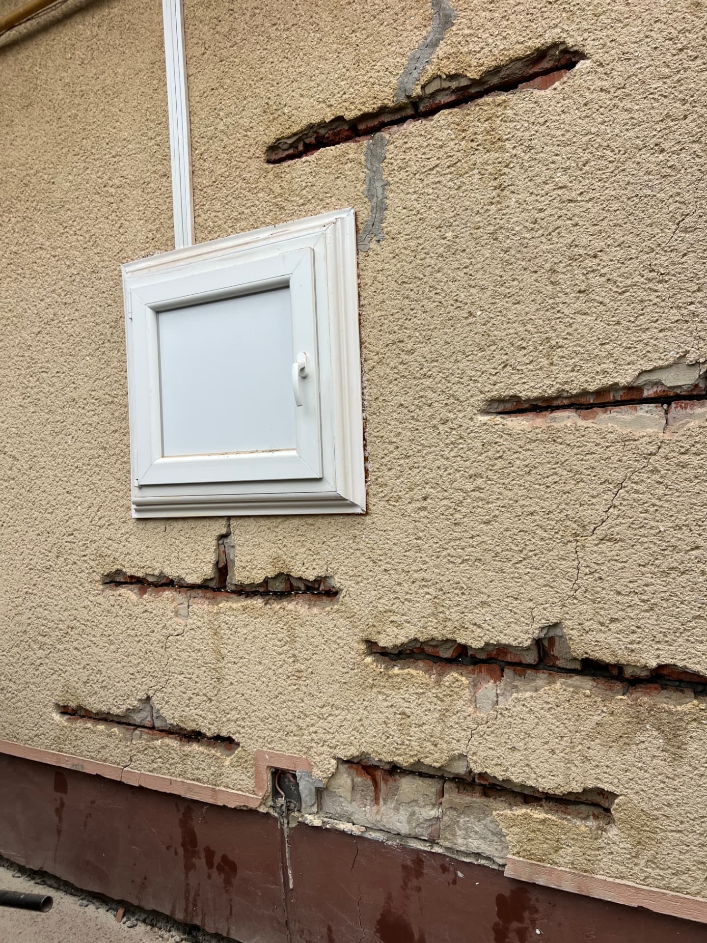 Hornyok a téglafalban egy pinceablak körül